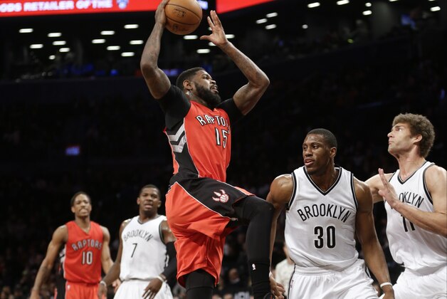 Toronto Raptors' Amir Johnson (15) shoots over Brooklyn Nets' Thaddeus Young (30) and Brook Lopez (11) during the first half of an NBA basketball game Friday, April 3, 2015, in New York.  (AP Photo/Frank Franklin II)