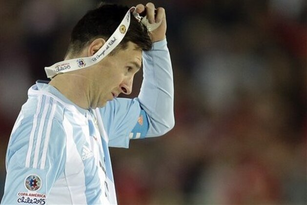Argentina's Lionel Messi takes off the Copa America silver medal after the final game with Chile at the National Stadium in Santiago, Chile, Saturday, July 4, 2015. Chile's goalkeeper Claudio Bravo made a save and striker Alexis Sanchez converted the winning penalty as host Chile defeated Argentina 4-1 in a shootout after a 0-0 draw in the Copa America final.(AP Photo/Natacha Pisarenko)