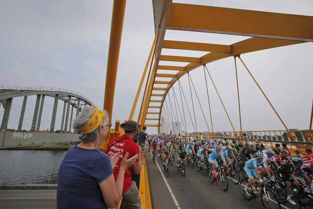 Spectators cheer as the pack passes a yellow-colored bridge on the outskirts of Utrecht during the second stage of the Tour de France cycling race over 166 kilometers (103 miles) with start in Utrecht and finish in Neeltje Jans, Netherlands, Sunday, July 5, 2015. (AP Photo/Christophe Ena)
