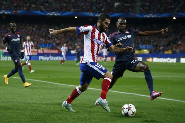 Atletico's Arda Turan, left tries to get past Olympiakos' Eric Abidal during a Group A Champions League soccer match between Atletico de Madrid and Olympiakos at the Vicente Calderon stadium in Madrid, Spain, Wednesday Nov. 26, 2014. (AP Photo/Andres Kudacki)