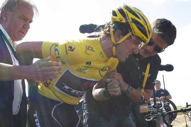 Switzerland's Fabian Cancellara, wearing the overall leader's yellow jersey, is treated for a back injury after crashing with several other riders during the third stage of the Tour de France cycling race over 159.5 kilometers (99.1 miles) with start in Antwerp and finish in Huy, Belgium, Monday, July 6, 2015. (AP Photo/Christophe Ena)