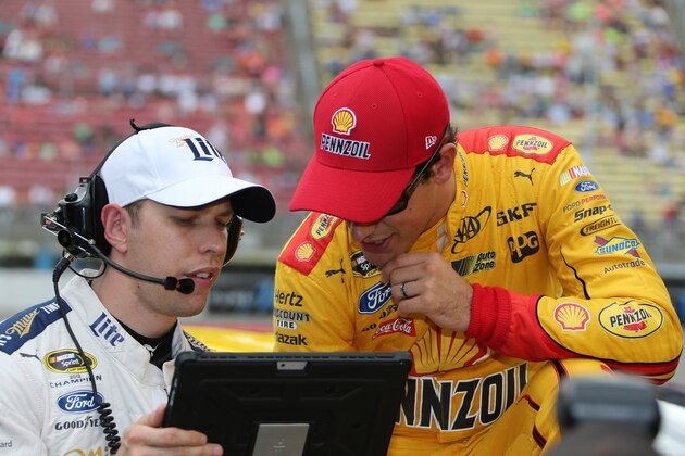 Brad Keselowski, left, and Joey Logano look over a monitor after qualifying for Sunday's NASCAR Sprint Cup series auto race at Michigan International Speedway, Friday, June 12, 2015, in Brooklyn, Mich. (AP Photo/Bob Brodbeck)