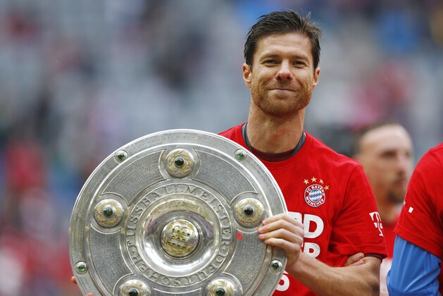 Bayern’s Xabi Alonso from Spain holds the trophy as the team celebrate winning the Bundesliga title after the German first division Bundesliga soccer match between FC Bayern Munich and FSV Mainz 05 at the Allianz Arena in Munich, Germany, Saturday, May 23, 2015. (AP Photo/Matthias Schrader)