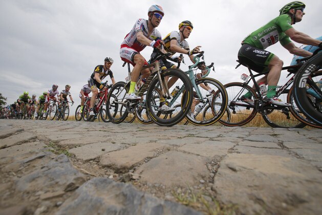 Germany's Andre Greipel, wearing the best sprinter's green jersey, right, Robert Gesink of the Netherlands, second right, and Norway's Alexander Kristoff, center in red and white jersey ride in the pack as it passes over the first cobblestone sector near Pont-a-Celles during the fourth stage of the Tour de France cycling race over 223.5 kilometers (138.9 miles) with start in Seraing, Belgium, and finish in Cambrai, France, Tuesday, July 7, 2015. (AP Photo/Christophe Ena)