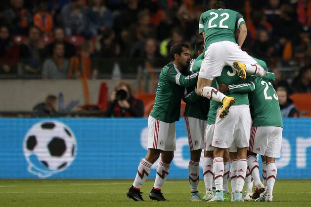 Mexico players celebrate with Mexico's Carlos Vela, not visible, after he scored a goal during the international friendly soccer match between the Netherlands and Mexico at ArenA stadium in Amsterdam, Netherlands, Wednesday, Nov. 12, 2014. (AP Photo/Peter Dejong)