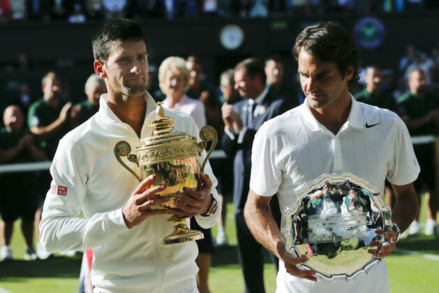 Serbia's Novak Djokovic, left, holds his trophy after defeating Switzerland's Roger Federer, right, in the men's singles final match at the All England Lawn Tennis Championships in Wimbledon, London, Sunday, July 6, 2014. (AP Photo/Ben Curtis)