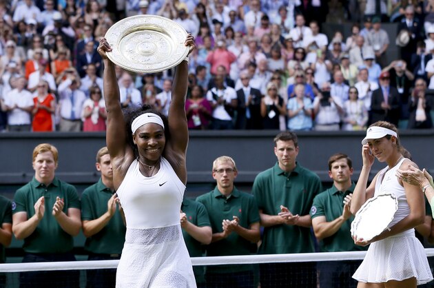 Serena Williams of the United States holds up the trophy after winning the women's singles final against Garbine Muguruza of Spain, background, at the All England Lawn Tennis Championships in Wimbledon, London, Saturday July 11, 2015. (AP Photo/Kirsty Wigglesworth)