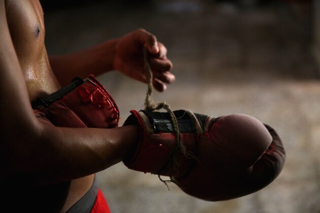 HAVANA, CUBA - MAY 09:  Jaime Poradius, 16-years-old, takes off his boxing gloves after a training session at the Salvador Allende Sports Complex on May 9, 2015 in Alamar, Cuba.  Alamar is a suburb of Havana. The town, which is about 30 minutes east of Havana, was built in the 1970Õs when the city center to supply much need housing to the people of Cuba. The gym where kids work out here is run by a coach Lazaro Goyalo Perez Quintana. The gym is not much of a gym, but rather a small room under a now-empty Olympic size swimming pool. The room has one light, one punching bag, and a couple of bags filled with sand pinned up against the wall for the boxers to train with. 
Although baseball is known as the national sport of Cuba, boxing in the sport where they have achieved the greatest dominance at the Olympic Games. Since the 1968 Games, Cuba has won a total of 53 medals, and 33 of those have been gold medals Ñ no other country is even close to those numbers.  Boxing starts as early as eight-years old for boys in