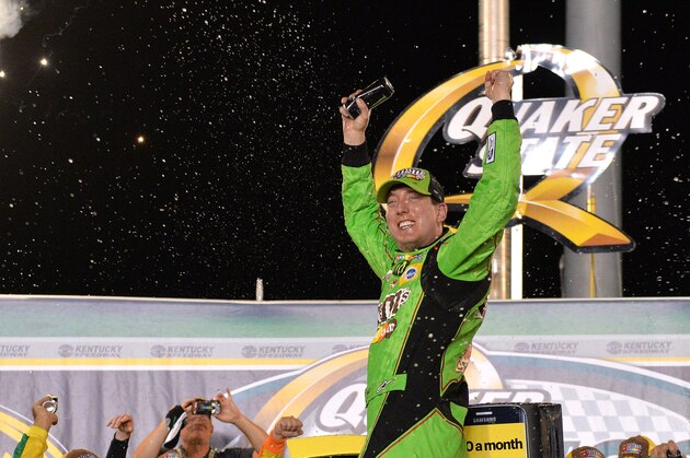 Kyle Busch stands on his car in Victory Lane after he won the NASCAR Sprint Cup series auto race at Kentucky Speedway in Sparta, Ky., Saturday, July 11, 2015. (AP Photo/Timothy D. Easley)