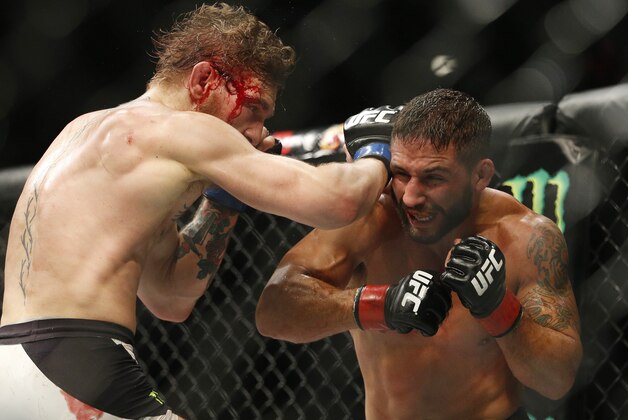 EDS NOTE GRAPHIC CONTENT - Conor McGregor, left, hits Chad Mendes during their interim featherweight title mixed martial arts bout at UFC 189 Saturday, July 11, 2015, in Las Vegas. (AP Photo/John Locher)