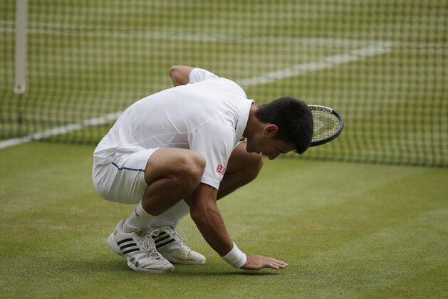 Novak Djokovic of Serbia touches the grass on Centre Court to celebrate winning the men's singles final against Roger Federer of Switzerland at the All England Lawn Tennis Championships in Wimbledon, London, Sunday July 12, 2015. Djokovic won the match 7-6, 6-7, 6-4, 6-3. (AP Photo/Pavel Golovkin)