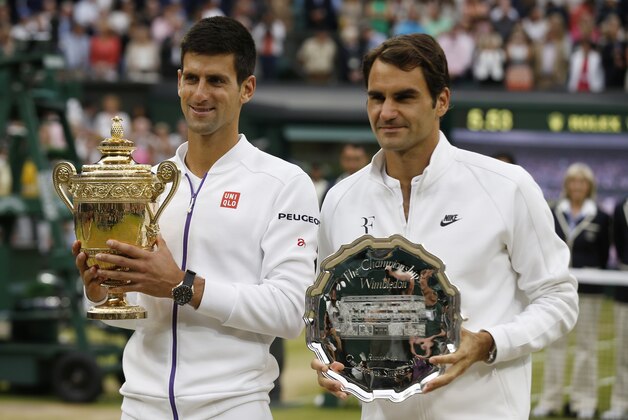 Novak Djokovic of Serbia, left, holds the trophy after winning the men's singles final against Roger Federer of Switzerland at the All England Lawn Tennis Championships in Wimbledon, London, Sunday July 12, 2015. Djokovic won the match 7-6, 6-7, 6-4, 6-3. (AP Photo/Alastair Grant)