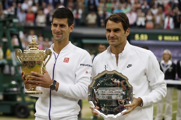 Novak Djokovic of Serbia, left, holds the trophy after winning the men's singles final against Roger Federer of Switzerland at the All England Lawn Tennis Championships in Wimbledon, London, Sunday July 12, 2015. Djokovic won the match 7-6, 6-7, 6-4, 6-3. (AP Photo/Alastair Grant)