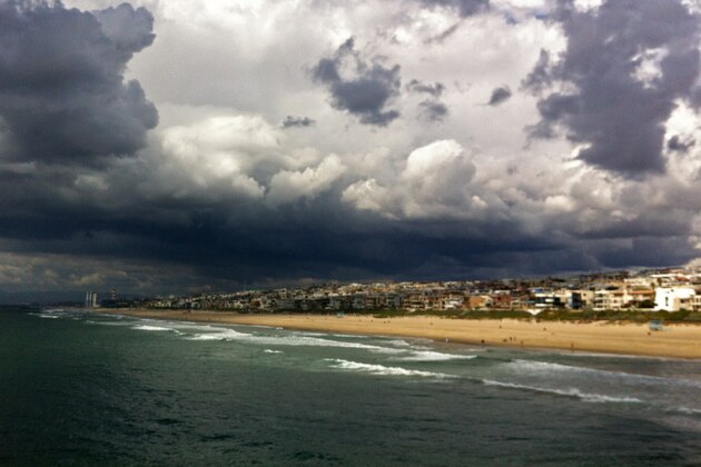 Sunlight breaks through a band of heavy clouds to illuminate the Strand at Manhattan Beach, Calif., Sunday, March 1, 2015. A winter storm brought heavy rain, lightning and small hail to parts of Southern California Sunday, raising the possibility of local flooding. The National Weather Service said the threat of showers will linger until Monday morning when the cold low-pressure system moves out. “Some areas will get a decent amount of rain. Other areas will get nothing,” said David Sweet, a meteorologist with the weather service’s Oxnard office. By Sunday afternoon heavy rain drenched Santa Monica, Venice, Brentwood and other communities on the west side of Los Angeles County. Venice also saw hail. (AP Photo/John Antczak)