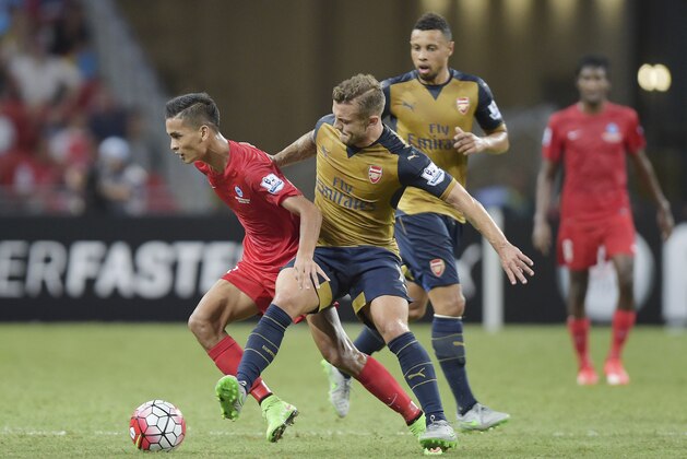 Arsenal midfielder Jack Wilshire, center, tackles Singapore Selection's Safuwan Baharudin, left, in their soccer match for the Barclays Asia Trophy in Singapore, Wednesday, July 15, 2015. (AP Photo/Joseph Nair)