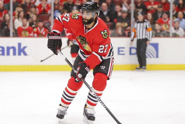 Chicago Blackhawks defenseman Johnny Oduya (27) looks to pass the pucks against the Minnesota Wild during the first period of an NHL hockey game Tuesday, April 7, 2015, in Chicago. (AP Photo/Kamil Krzaczynski)