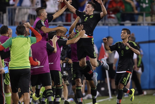 Mexico's Hector Herrera (6) jumps into his team mates arms after scoring a goal against Trinidad & Tobago during the second half of a CONCACAF Gold Cup soccer match in Charlotte, N.C., Wednesday, July 15, 2015. The match ended in a 4-4 draw. (AP Photo/Gerry Broome)