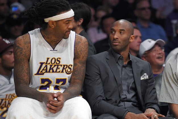 Los Angeles Lakers center Jordan Hill, left, talks with injured player Kobe Bryant during the first half of an NBA basketball game against the Dallas Mavericks, Sunday, March 8, 2015, in Los Angeles. (AP Photo/Mark J. Terrill)