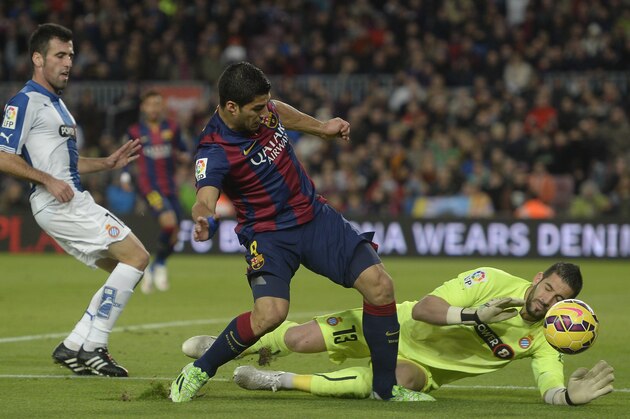 FC Barcelona's Luis Suarez, second left, duels for the ball against Espanyol's goalkeeper Kiko Casilla during a Spanish La Liga soccer match at the Camp Nou stadium in Barcelona, Spain, Sunday, Dec. 7, 2014. (AP Photo/Manu Fernandez)