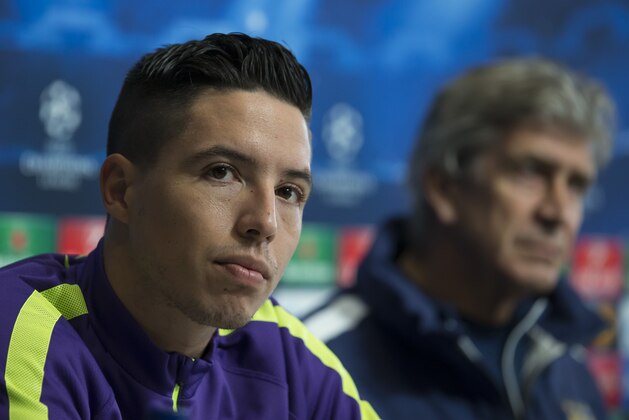 Manchester City's Samir Nasri, left, sits alongside manager Manuel Pellegrini at a press conference at the Etihad Stadium in Manchester, England, Monday, Feb. 23, 2015. Manchester City will play Barcelona on Tuesday in a Champions League Round of 16 soccer match. (AP Photo/Jon Super)