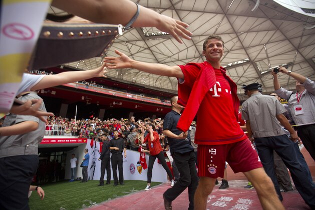 Bayern's Thomas Mueller high-fives spectators as he takes the field with his teammates for a practice at Beijing National Stadium, also known as the Birds Nest, in Beijing, Friday, July 17, 2015. Bayern Munich will play a friendly match against Valencia in the Chinese capital on Saturday. (AP Photo/Mark Schiefelbein)