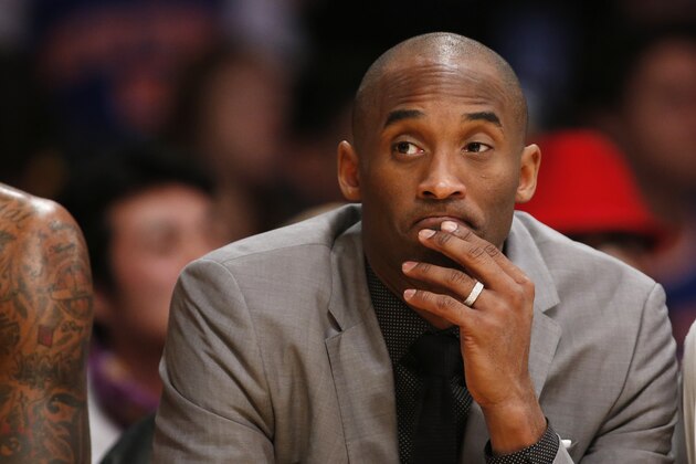 Los Angeles Lakers' Kobe Bryant, who is injured, sits on the bench in a suit against the New York Knicks during the first half of an NBA Basketball game, Thursday, March 12, 2015, in Los Angeles. (AP Photo/Danny Moloshok)
