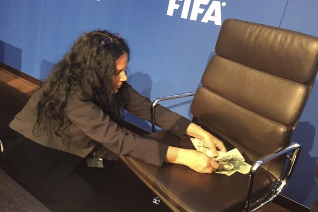 A woman collects bank notes after a comedian threw them during a FIFA press conference in Zurich, Switzerland, Monday, July 20, 2015. Sepp Blatter’s news conference at FIFA has been disrupted and delayed by a British comedian’s stunt protest. As Blatter took his seat, performer Simon Brodkin rose from a front-row seat to speak and shower the FIFA president with dollar bills.  (AP Photo/Rob Harris)