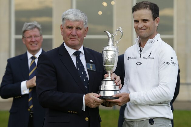 United States’ Zach Johnson, right, poses with the trophy as it is handed to him by R&A captain George Macgregor after he won a playoff after the final round at the British Open Golf Championship at the Old Course, St. Andrews, Scotland, Monday, July 20, 2015. (AP Photo/David J. Phillip)