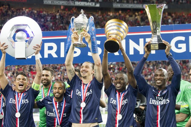 Paris Saint-Germain's (PSG) Brazilian defender Thiago Silva holding up the Ligue 1 trophy, Swedish forward Zlatan Ibrahimovic holding up the French Cup trophy, midfielder Blaise Matuidi holding the French League Cup and defender Zoumana Camara holding the Champions' Trophy as they celebrate after winning the French Cup final football match against Auxerre at the Stade de France stadium in Saint-Denis,  North of Paris, Saturday May 30, 2015. PSG won 1-0. (AP Photo/Jacques Brinon)