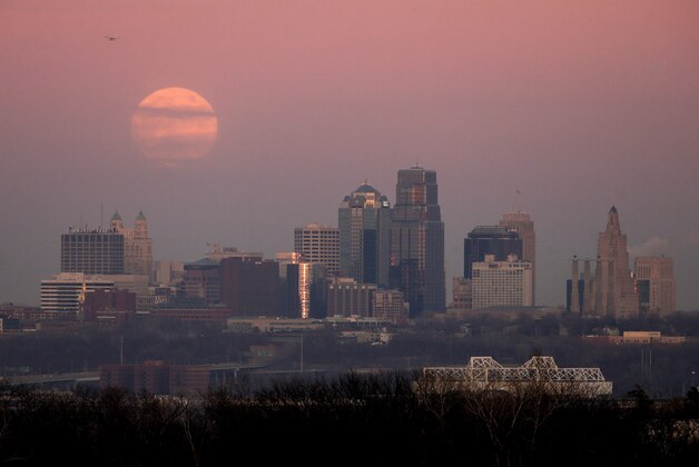 A full moon is shrouded in haze as it rises over the Kansas City, Mo. skyline at sunset Monday, Dec. 16, 2013. (AP Photo/Charlie Riedel)