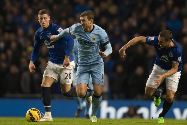Manchester City's Edin Dzeko, centre, fights for the ball against Everton's Ross Barkley, left, and Philip Jagielka during the English Premier League soccer match between Manchester City and Everton at the Etihad Stadium, Manchester, England, Saturday Dec. 6, 2014. (AP Photo/Jon Super)