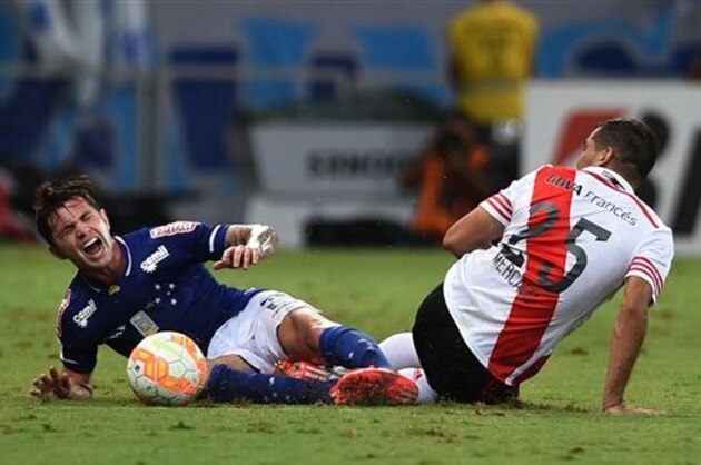 Eugenio Mena of Brazil's Cruzeiro, left, grimaces in pain while he fights for the ball with Gabriel Mercado of Argentina's River Plate during a Copa Libertadores quarter finals soccer match in Belo Horizonte, Brazil, Wednesday, May 27, 2015. (AP Photo/Eugenio Savio)