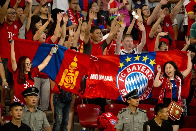 Bayern Munich fans hold a Mongolian flag, left, and a supporters' flag as they cheer for their team during Bayern's friendly soccer match against Valencia in Beijing, Saturday, July 18, 2015. Bayern Munich beat Valencia, 4-1. (AP Photo/Mark Schiefelbein)