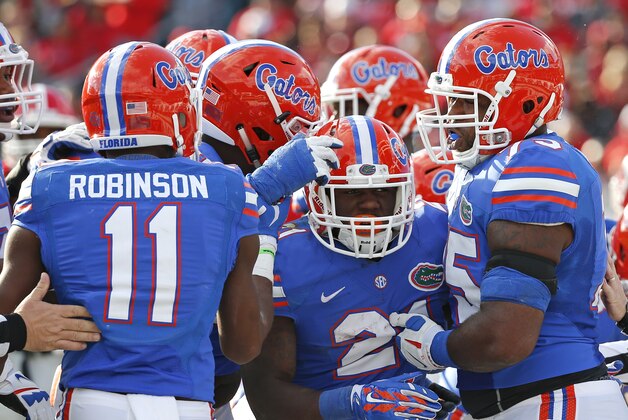 Florida running back Kelvin Taylor, center, celebrates a touchdown run with teammates including Demarcus Robinson (11) and Chaz Green, right, during the first half of an NCAA college football game against Georgia in Jacksonville, Fla., Saturday, Nov. 1, 2014. (AP Photo/Stephen B. Morton)