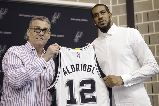 LaMarcus Aldridge, right, poses with San Antonio Spurs general manager R.C. Buford, left, and his new jersey during a news conference at the team's practice facility as he is formally introduced after he signed with the San Antonio Spurs NBA basketball team, Friday, July 10, 2015, in San Antonio. (AP Photo/Eric Gay)