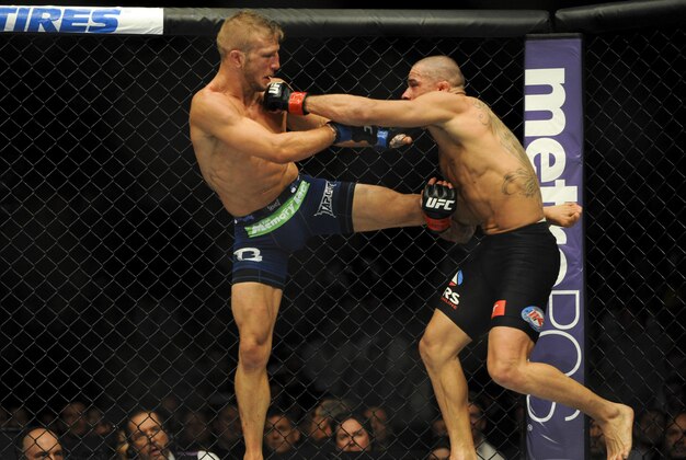 May 24, 2014; Las Vegas, NV, USA;  Renan Barao (red) takes a kick from TJ Dillashaw (blue) during their UFC 173 bantamweight championship bout at MGM Grand Garden Arena. Dillashaw won the bout by way of TKO. Mandatory Credit: Stephen R. Sylvanie-USA TODAY Sports