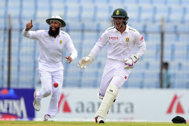 South Africa captain Hashim Amla (L) and wicketkeeper Quinton de Kock (R) react after the dismissal of the Bangladesh cricketer Imrul Kayes during the second day of the first cricket Test match between Bangladesh and South Africa at the Zahur Ahmed Chowdhury Stadium in Chittagong on July 22, 2015. AFP PHOTO/ Munir uz ZAMAN        (Photo credit should read MUNIR UZ ZAMAN/AFP/Getty Images)