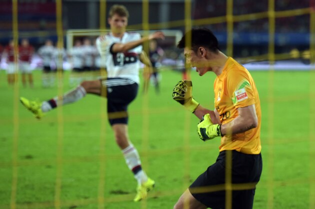 Guangzhou Evergrande's Chinese goalkeeper Zeng Cheng (R) reacts after saving a shot by Bayern Munich's forward Thomas Mueller at the penalty shootout during a friendly football match between Guangzhou Evergrande and Bayern Munich in Guangzhou on July 23, 2015. Guangzhou Evergrande defeated Bayern Munich 5:4 in the penalties shootout after tying the match 0-0.  AFP PHOTO / JOHANNES EISELE        (Photo credit should read JOHANNES EISELE/AFP/Getty Images)