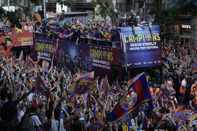 Fans cheer as FC Barcelona players ride on the team bus during celebrations in Barcelona, Spain Sunday June 7, 2015 after winning the Champions League final soccer match Saturday by beating Juventus Turin 3-1. Barcelona won the triple this season winning the Spanish League title, the Copa del Rey and the Champions League. (AP Photo/Emilio Morenatti)