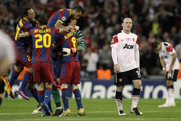 Manchester United's Wayne Rooney, right, reacts as Barcelona players celebrate winning the Champions League final soccer match at Wembley Stadium, London, Saturday, May 28, 2011. (AP Photo/Matt Dunham)