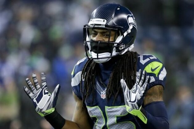 FILE - In this Jan. 10, 2015, file photo, Seattle Seahawks cornerback Richard Sherman gestures during warmups before an NFL divisional playoff football game against the Carolina Panthers in Seattle. Whether by design or coincidence, Aaron Rodgers didn't throw in cornerback Richard Sherman's direction in the teams' first meeting this season.  (AP Photo/Elaine Thompson, File)
