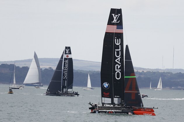 Oracle Team USA, right, and SoftBank Team Japan, left, boats who will be competing in the America's Cup World Series, parades along the waterfront in Portsmouth, England, Thursday, July 23, 2015. The event in Portsmouth is one of the America's Cup World Series qualifying events, ahead of the 35th Americas Cup in 2017. Racing takes place on July 25 and 26. (AP Photo/Kirsty Wigglesworth)