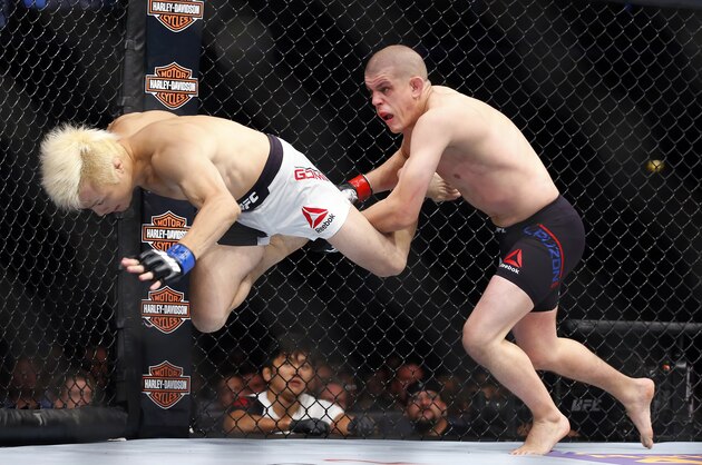 Takanori Gomi, left, tries to get away from Joe Lauzon during their lightweight mixed martial arts bout during UFC Chicago on Saturday, July 25, 2015, in Chicago. (AP Photo/Jeff Haynes)
