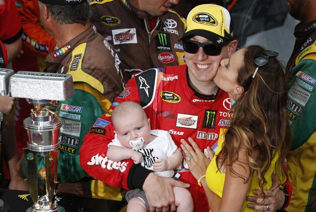 Jul 26, 2015; Indianapolis, IN, USA; NASCAR Sprint Car driver Kyle Busch gets a kiss from  wife Samantha Busch while holding son Brexton Locke Busch after winning the Crown Royal 400 at Indianapolis Motor Speedway. Mandatory Credit: Brian Spurlock-USA TODAY Sports