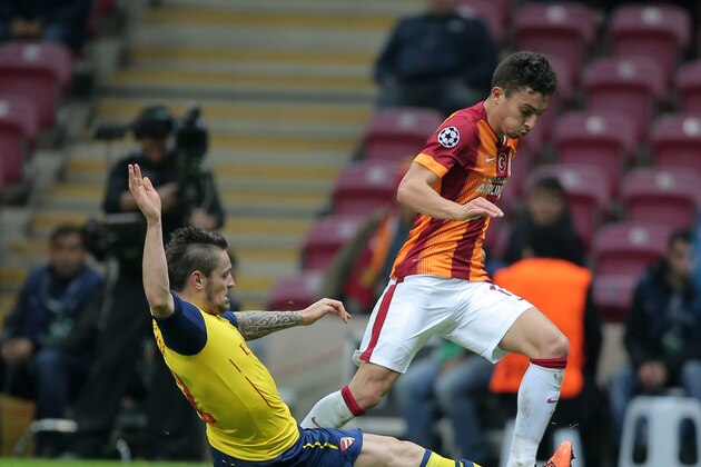 Arsenal's Mathieu Debuchy, left, and Alex Telles of Galatasaray fight for the ball during their Champions League Group D soccer match at the Turk Telekom Arena Stadium in Istanbul, Turkey, Tuesday, Dec. 9, 2014. (AP Photo)