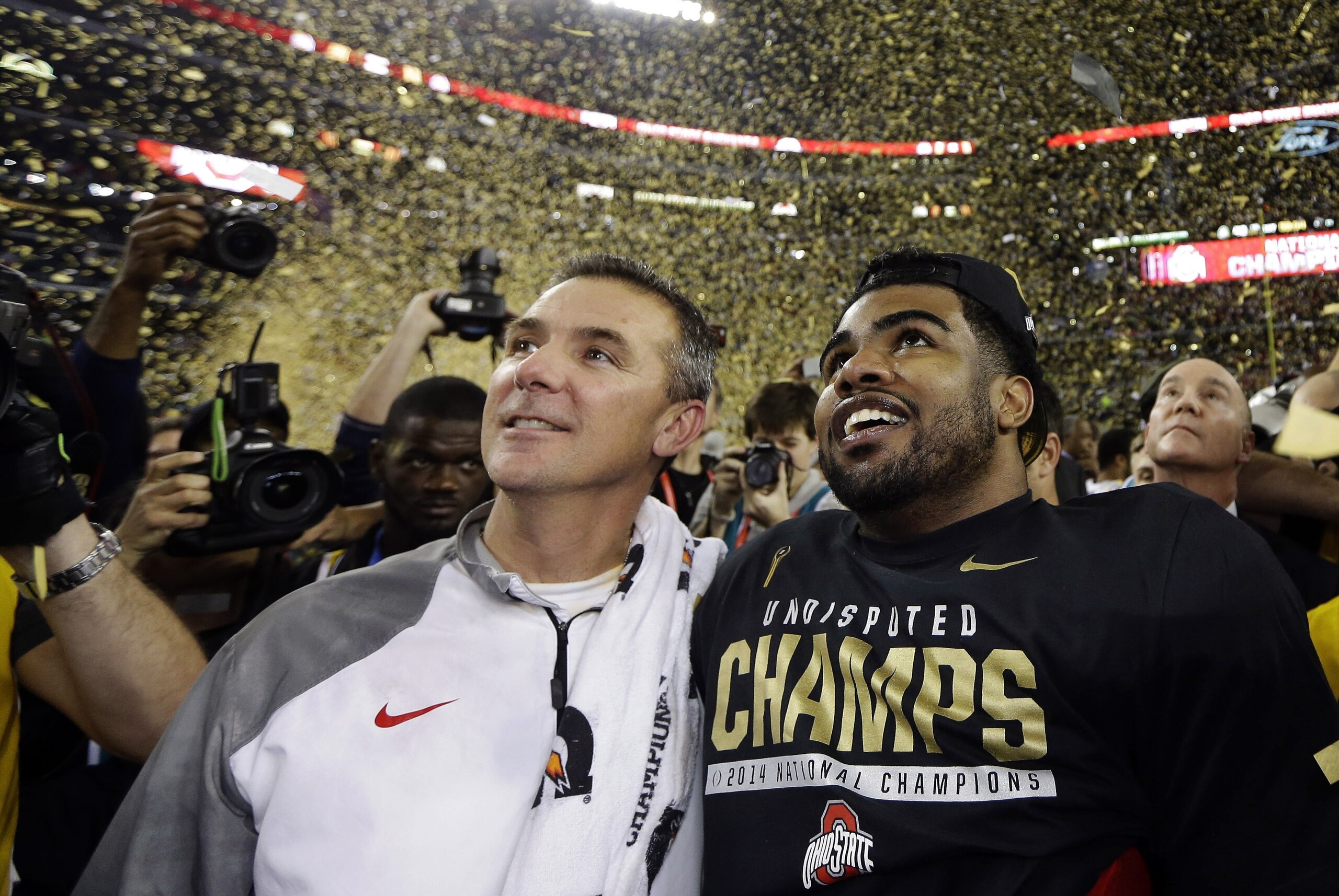 FILE - In this Jan. 12, 2015, file photo, Ohio State head coach Urban Meyer, left, and Ezekiel Elliott celebrate after they defeated Oregon 42-20 in the NCAA college football playoff championship game in Arlington, Texas. According to an NCAA report to be released Tuesday, April 14, 2015, the 39 postseason FBS games distributed $505.9 million to the participating conferences and schools. The schools spent $100.2 million to take part in bowl games. The increase in payouts is due mostly to the increased value of media deals with the seven games, six bowls and a national championship game, that are part of the College Football Playoff. (AP Photo/David J. Phillip, File)