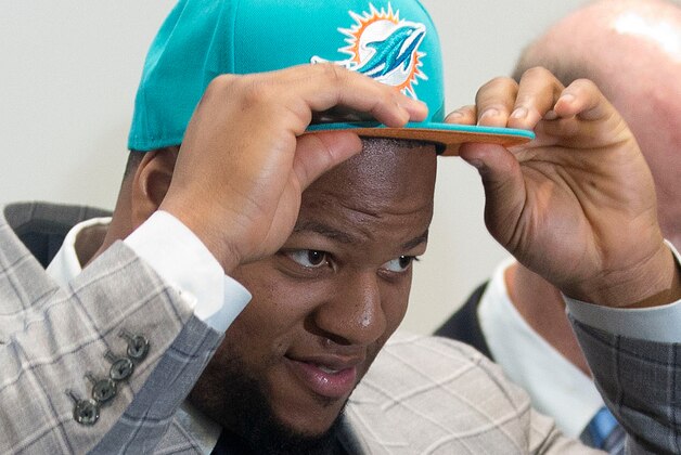 Miami Dolphins' Ndamukong Suh dons on a Dolphins cap during an NFL football news conference in Davie, Fla., Wednesday, March 11, 2015. Suh signed a $114 million, six-year deal with the Dolphins on Wednesday (AP Photo/J Pat Carter)