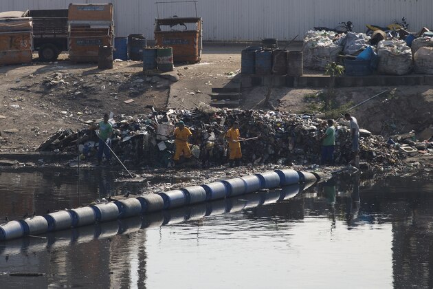 In this July 28, 2015 photo, workers remove garbage collected by floating waste barriers in a canal at the Mare slum complex, in Rio de Janeiro, Brazil. Rio's historic sewage problem spiraled over the past decade as the population exploded with many of the metropolitan area's 12 million residents settling in the vast slums that ring the bay. Waste flows into over 50 streams that empty into the once-crystalline Guanabara Bay. (AP Photo/Silvia Izquierdo) In this July 28, 2015 photo, workers remove garbage collected by floating waste barriers in a canal at the Mare slum complex, in Rio de Janeiro, Brazil. Rio's historic sewage problem spiraled over the past decade as the population exploded with many of the metropolitan area's 12 million residents settling in the vast slums that ring the bay. Waste flows into over 50 streams that empty into the once-crystalline Guanabara Bay. (AP Photo/Silvia Izquierdo)