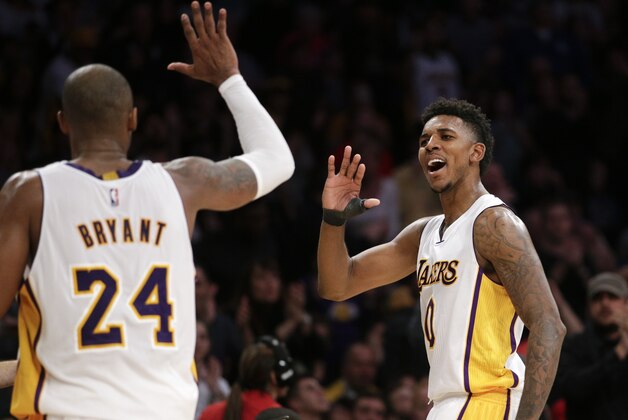 Los Angeles Lakers' Kobe Bryant, left, and Nick Young high-five during the second half of an NBA basketball game against the Toronto Raptors Sunday, Nov. 30, 2014, in Los Angeles. The Lakers won 129-122 in overtime. (AP Photo/Jae C. Hong)