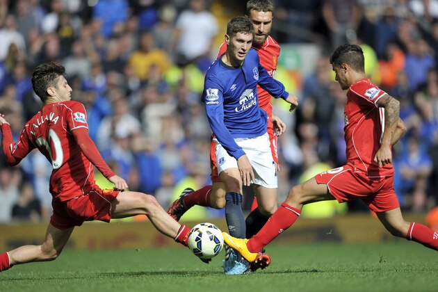 Liverpool's Adam Lallana left, and Philippe Coutinho right, tackle Everton's John Stones centre, during their English Premier League soccer match at Anfield in Liverpool, England, Saturday Sept. 27, 2014. (AP Photo/Clint Hughes)